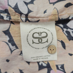 Close-up of a label on a floral-patterned fabric with a wooden button.