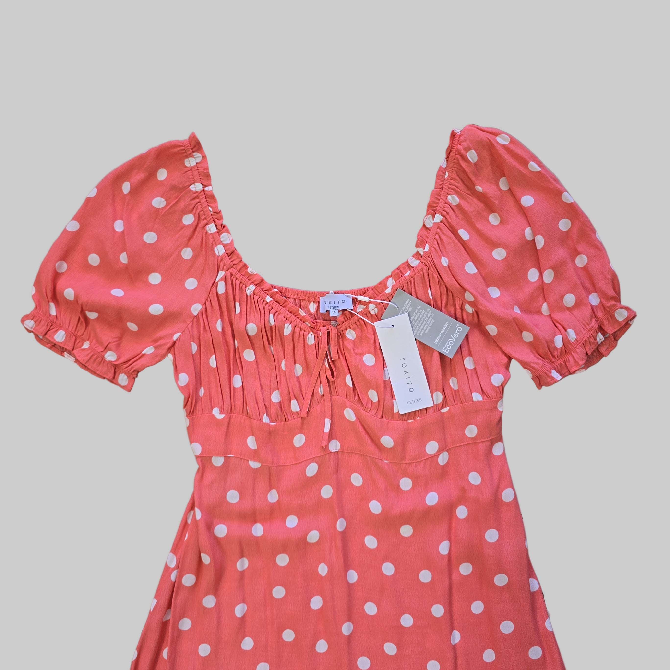 Pink polka dot dress with tags on a tiled floor