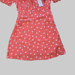 Pink dress with white polka dots on a tiled floor