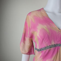 Close-up of a pink and gold textured fabric with a silver lace on a gray background