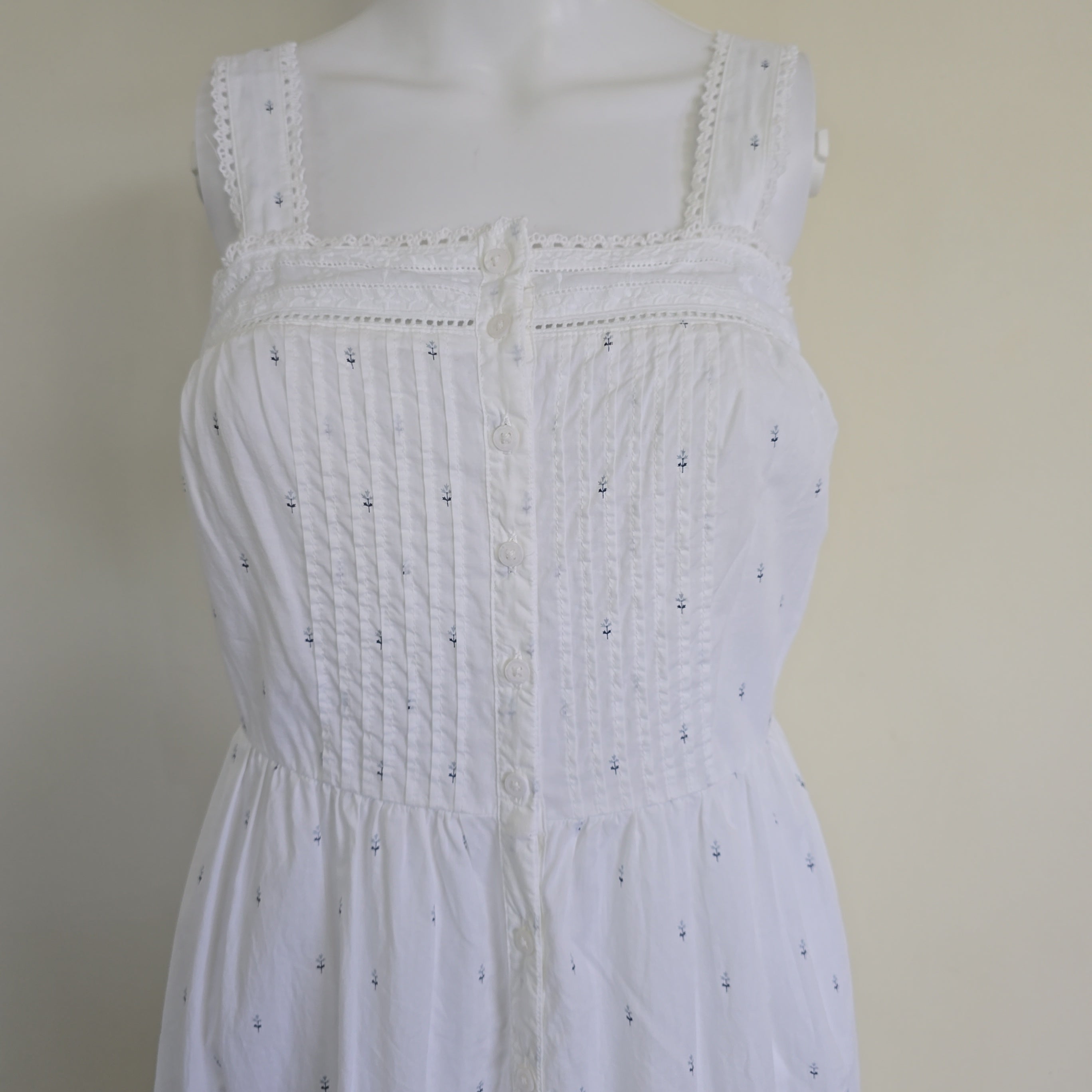 White top with intricate detailing on a beige background