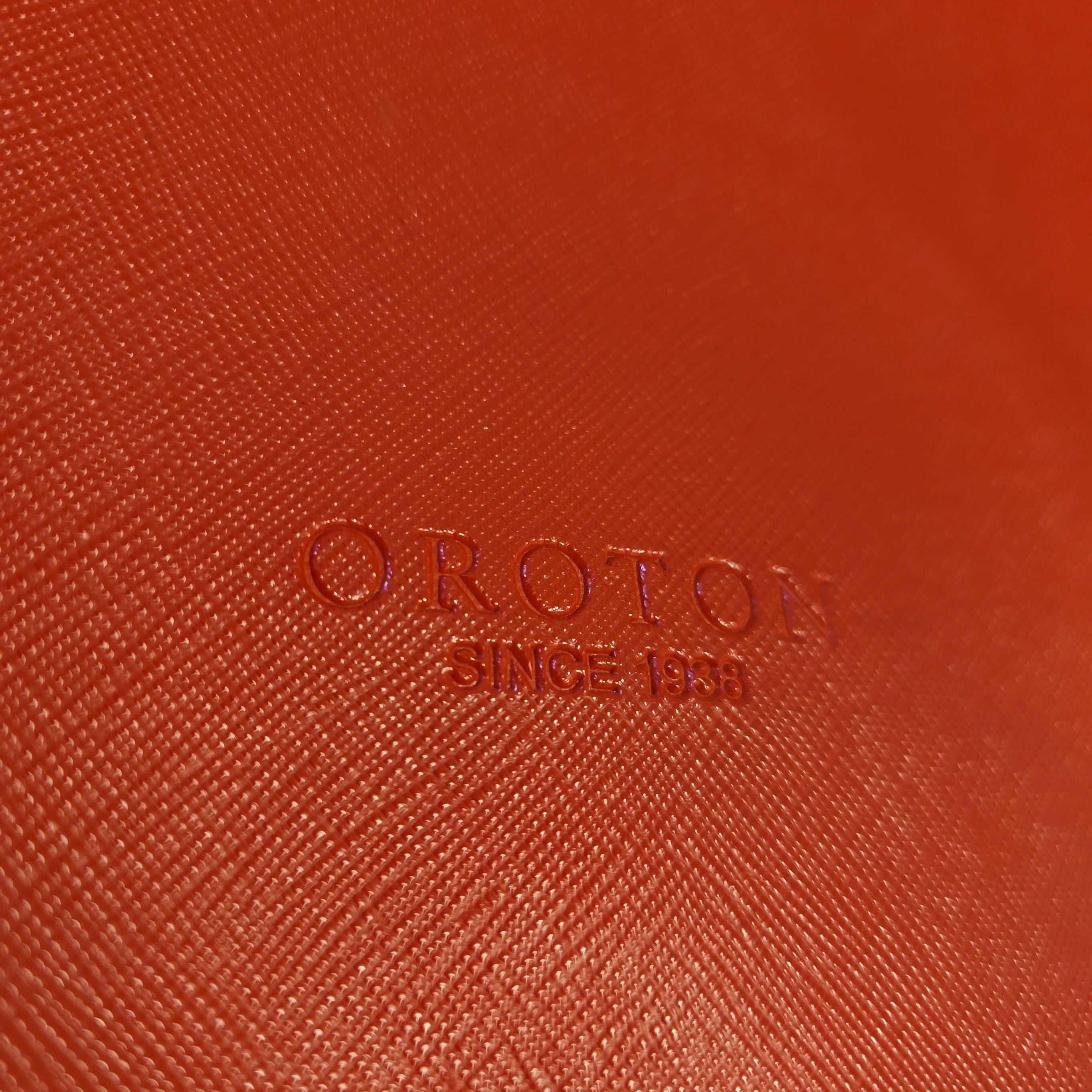 Close-up of a red textured surface with 'OROTON' branding.