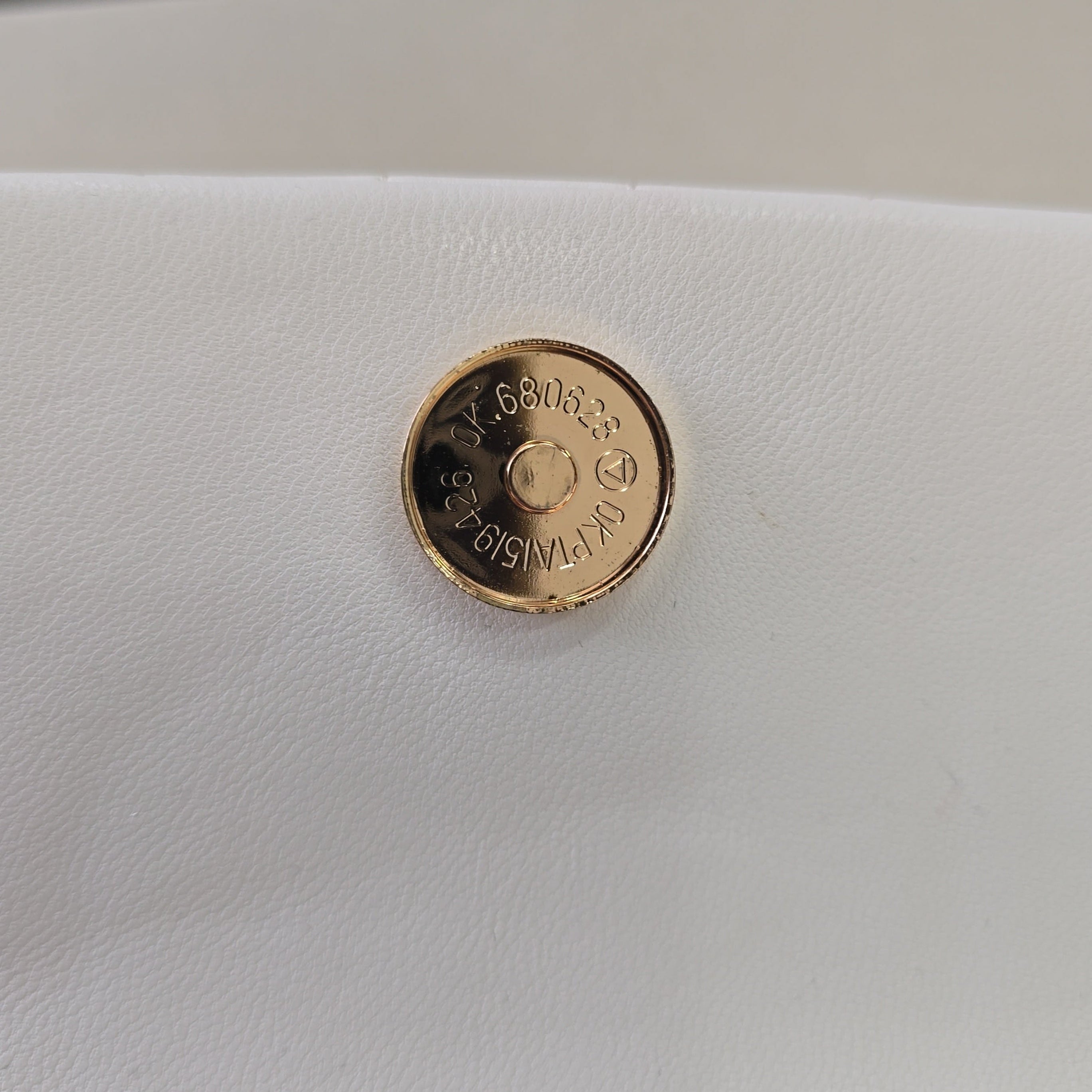 Gold button on a white leather surface