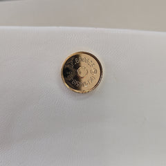 Gold button on a white leather surface