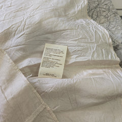 Close-up of a white comforter with a tag on a textured surface