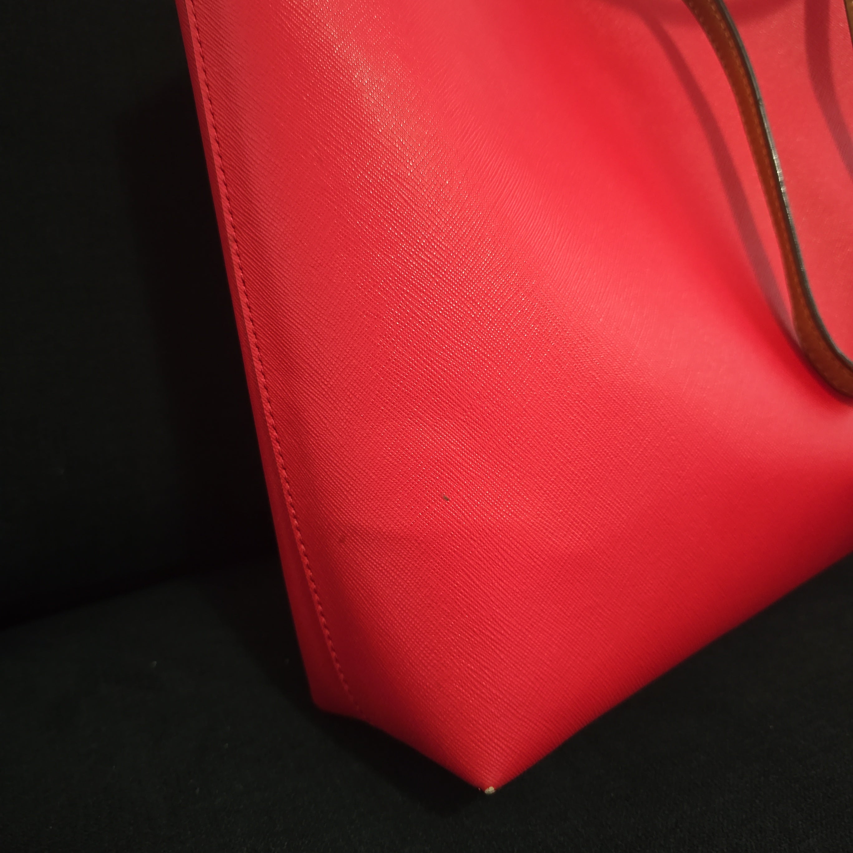 Red handbag with a visible brand logo on a light background