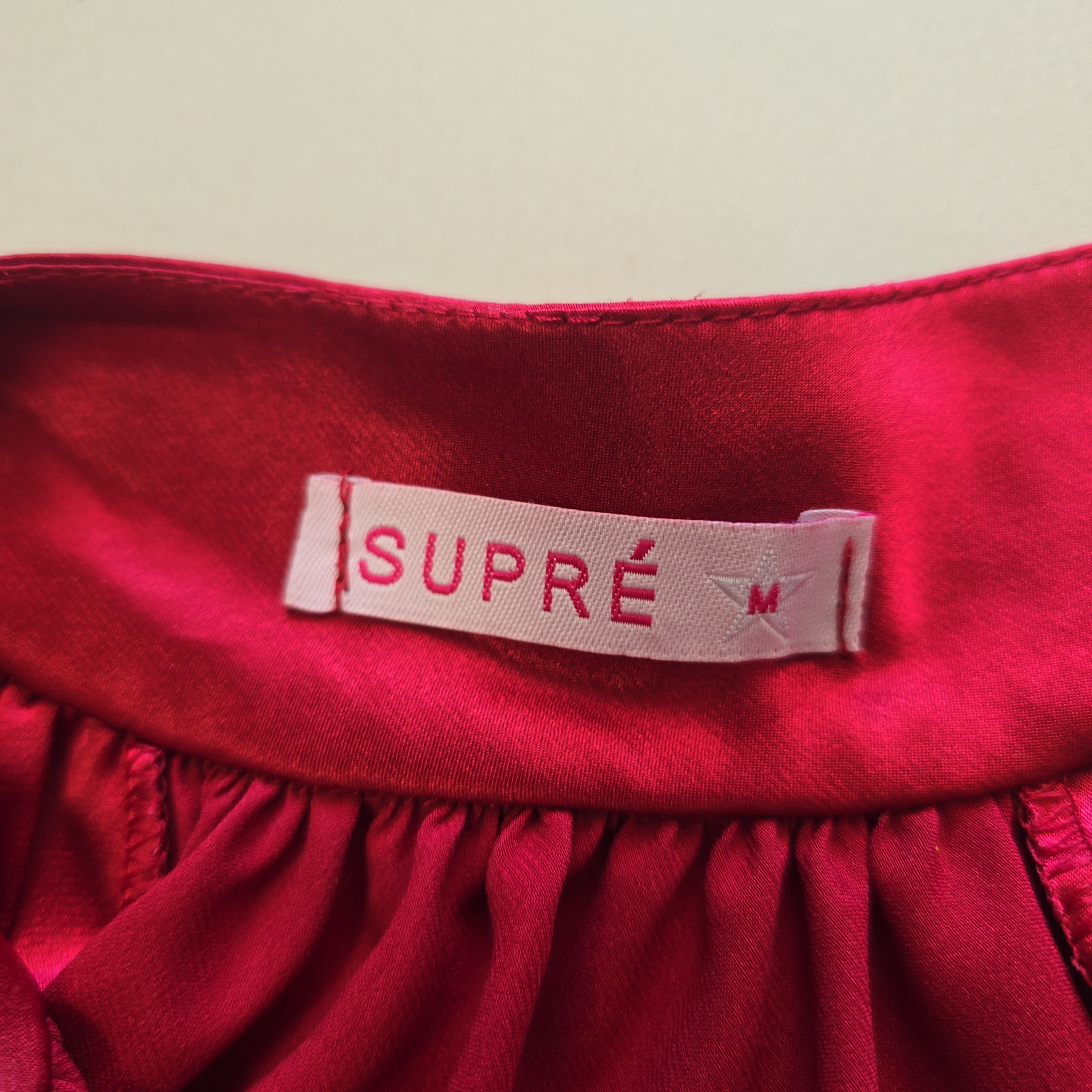 Red fabric with a Supre label on a beige background