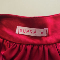 Red fabric with a Supre label on a beige background