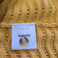 Auguste coffee package on a textured mustard yellow fabric background