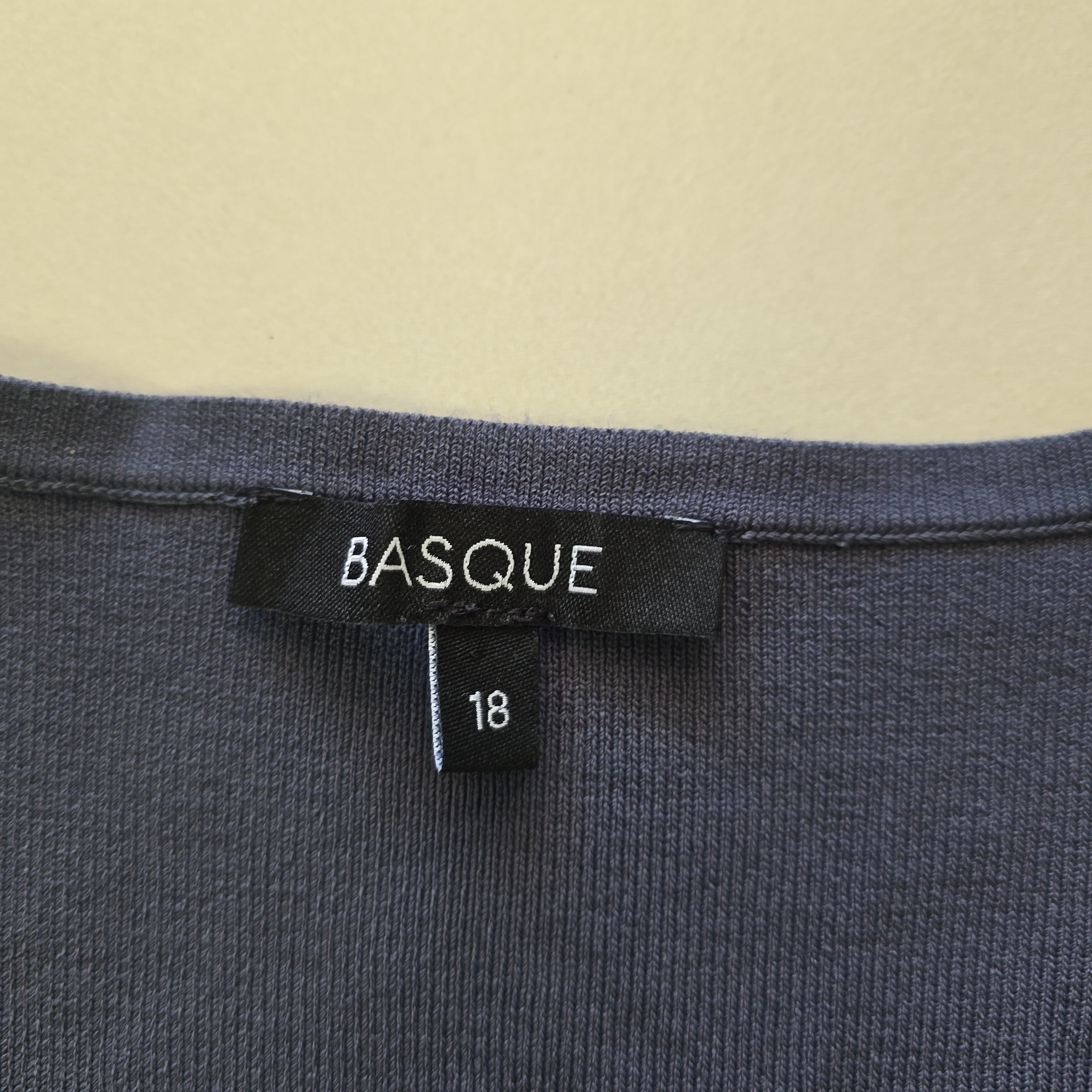 Close-up of a Basque brand label on a piece of clothing with a beige background.