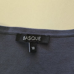 Close-up of a Basque brand label on a piece of clothing with a beige background.