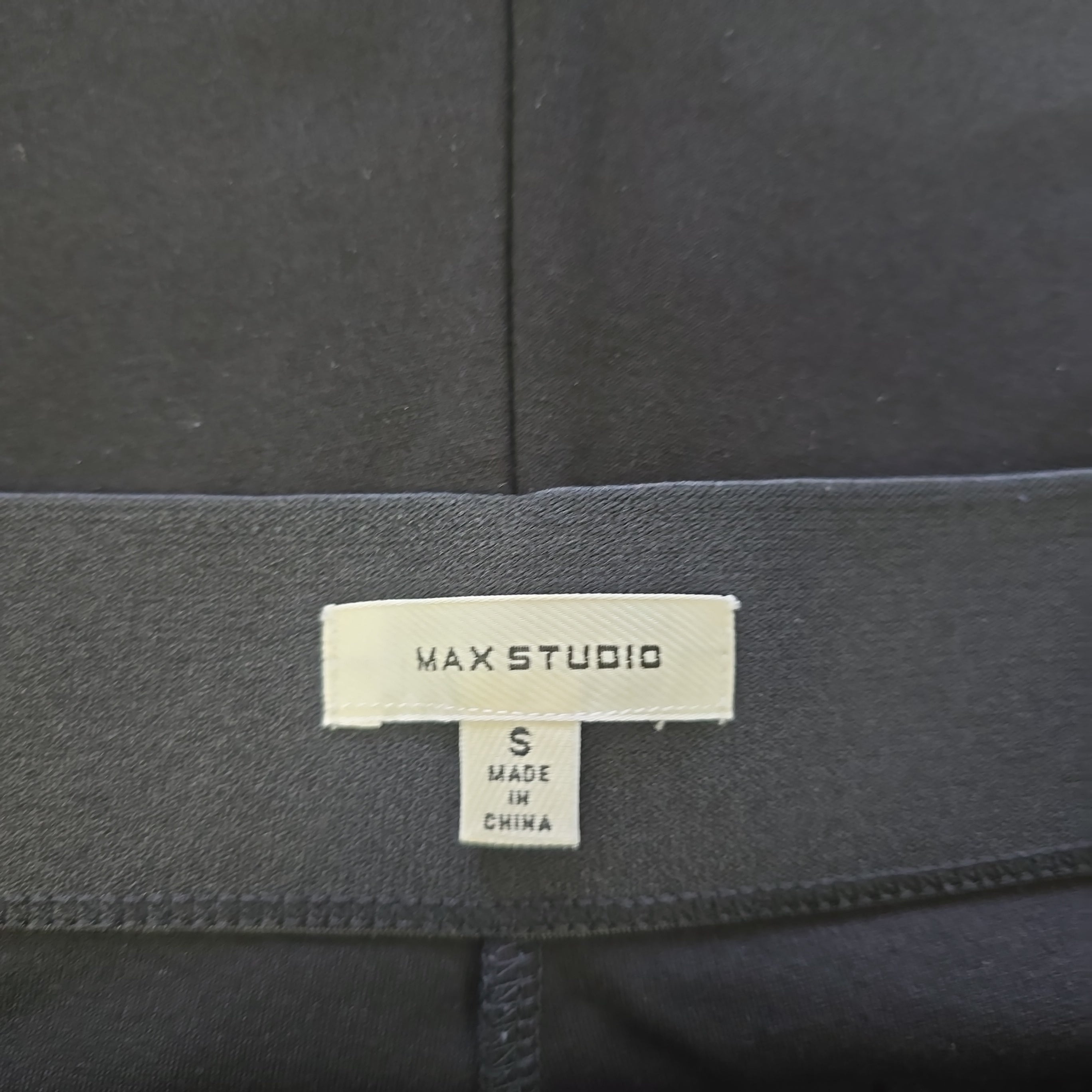 Black fabric with a 'MAX STUDIO' label on a dark background