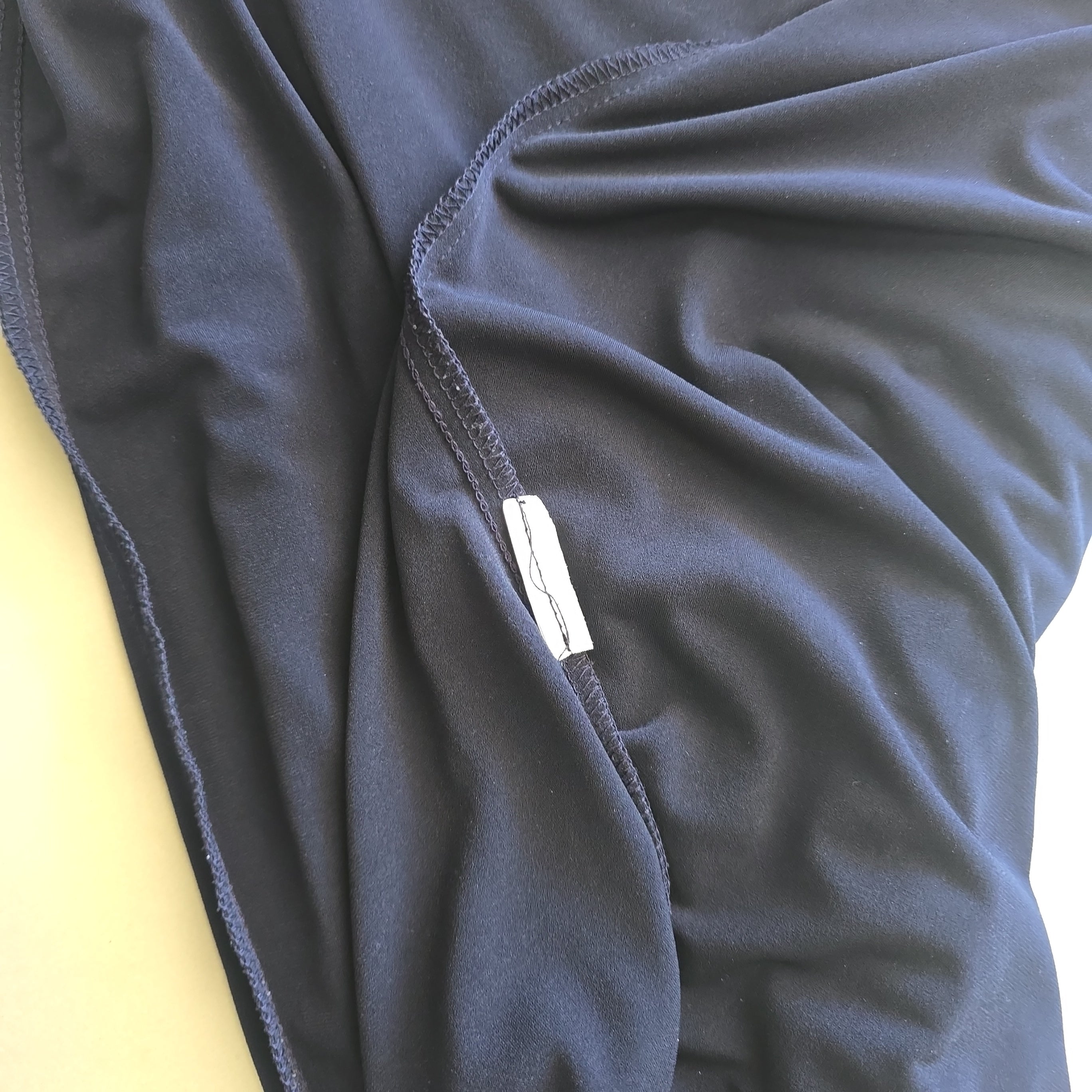 Close-up of a dark blue fabric with a brand label on a yellow surface