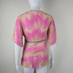 Mannequin wearing a pink and gold patterned garment on a plain background