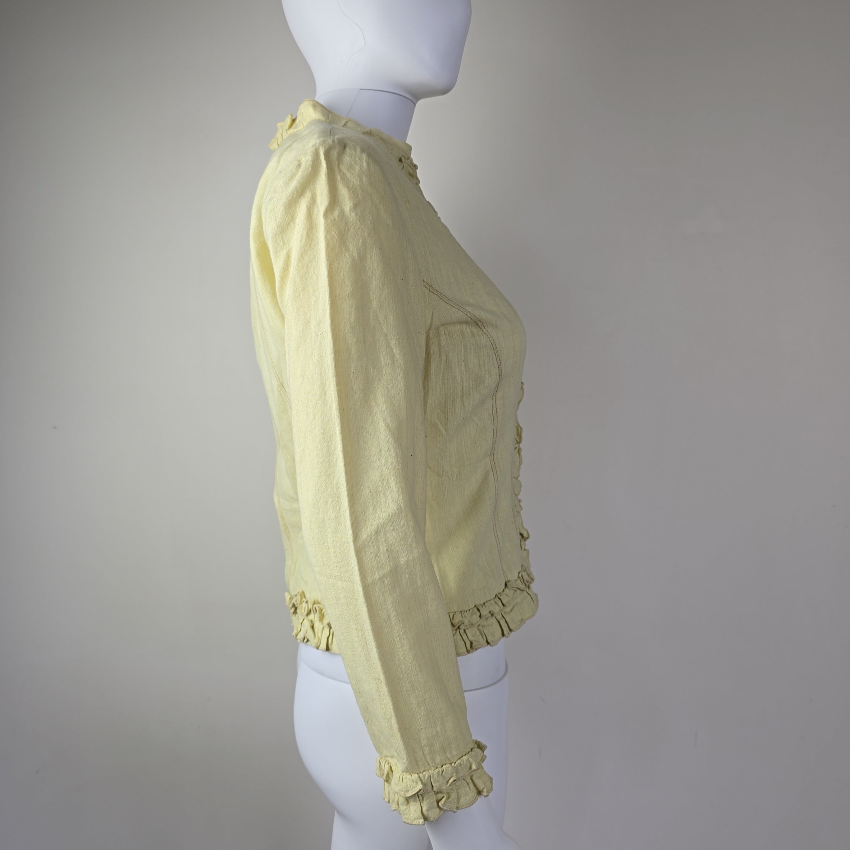 Light yellow jacket with frill details on a light background
