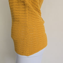 Yellow knitted sleeve on a mannequin against a neutral background