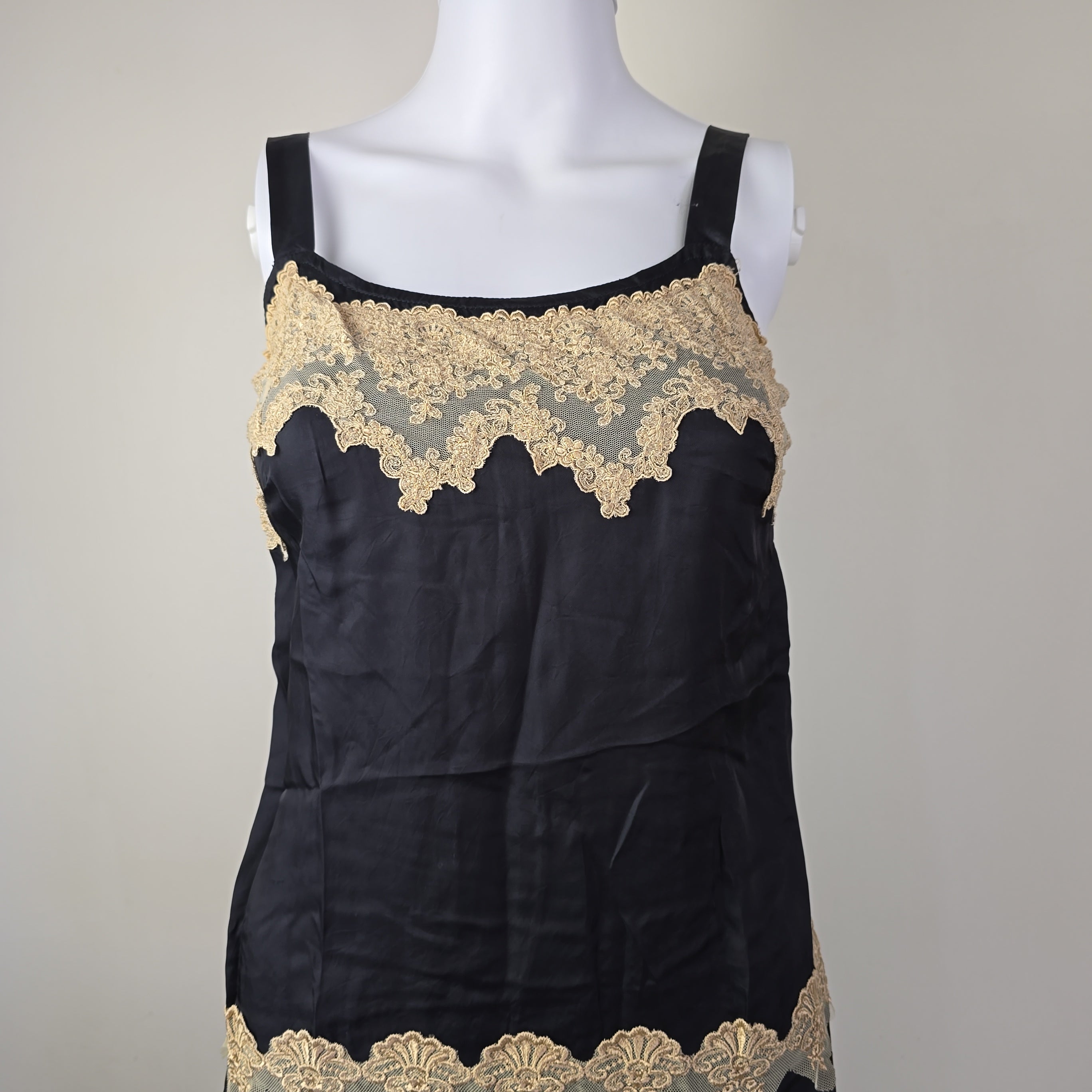 Black dress with gold lace trim on a mannequin against a gray background
