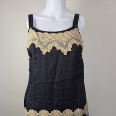 Black dress with gold lace trim on a mannequin against a gray background