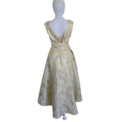 Gold lace dress on a mannequin against a plain background