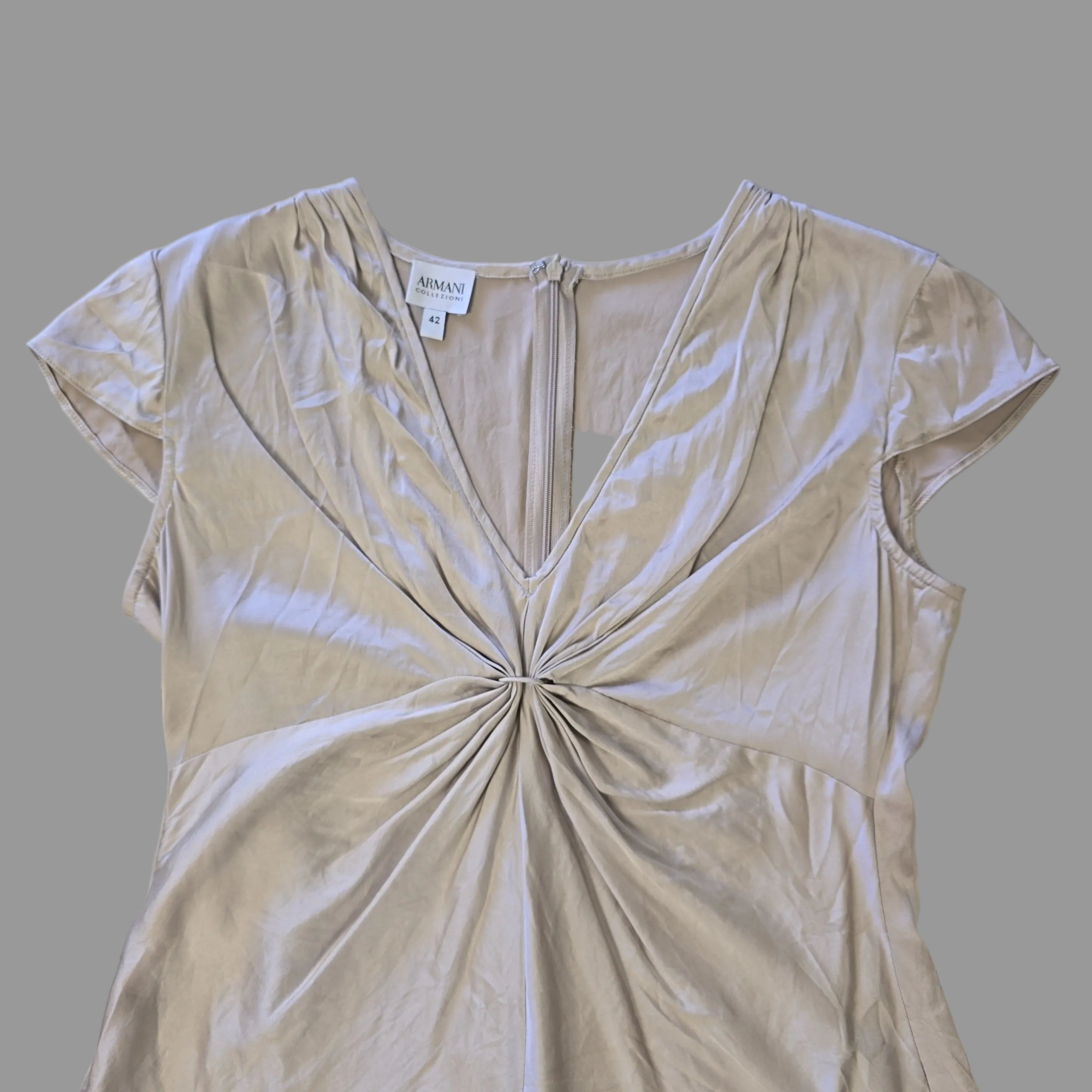 Beige top with a knot detail on alight floor