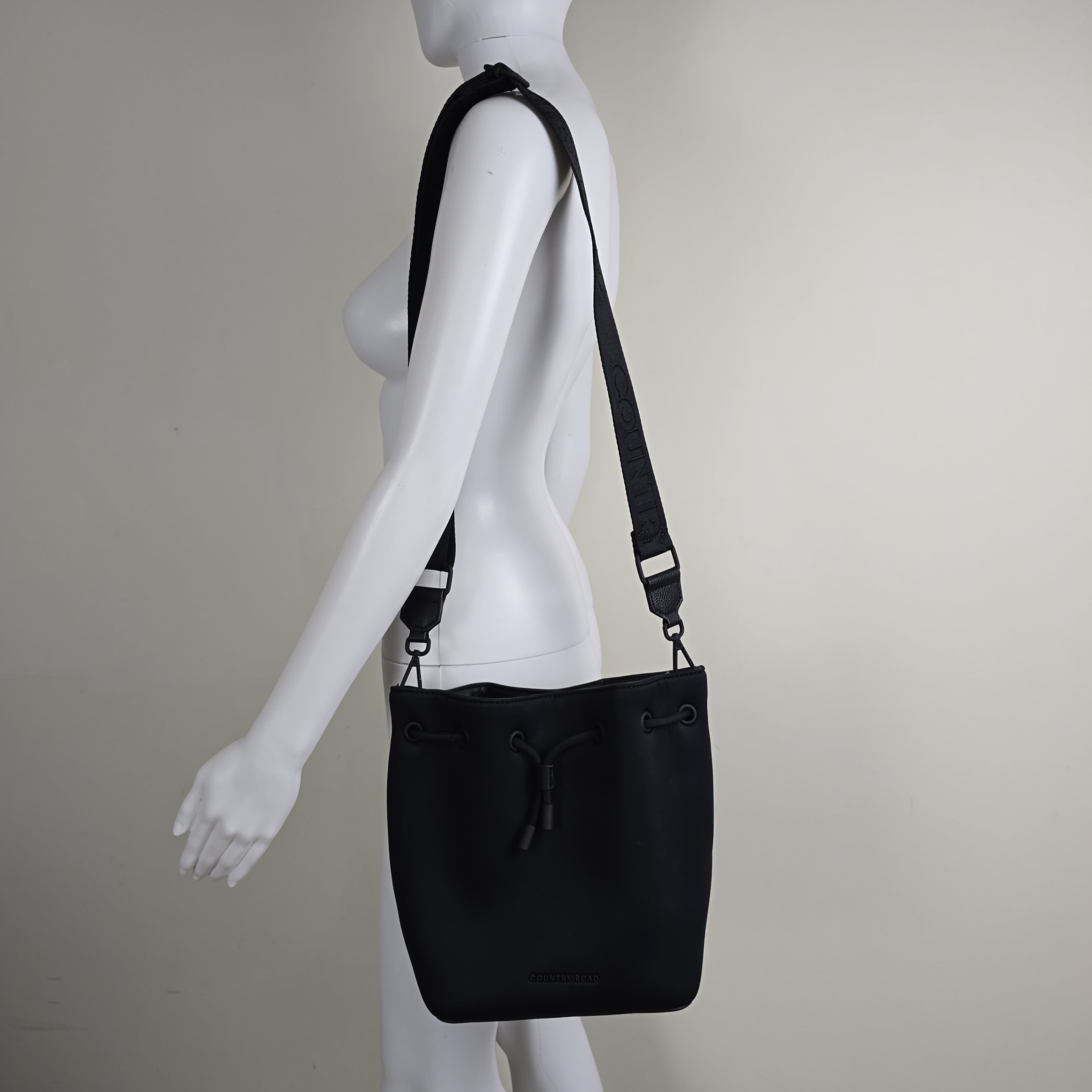 Black bag with a strap on a mannequin against a plain background