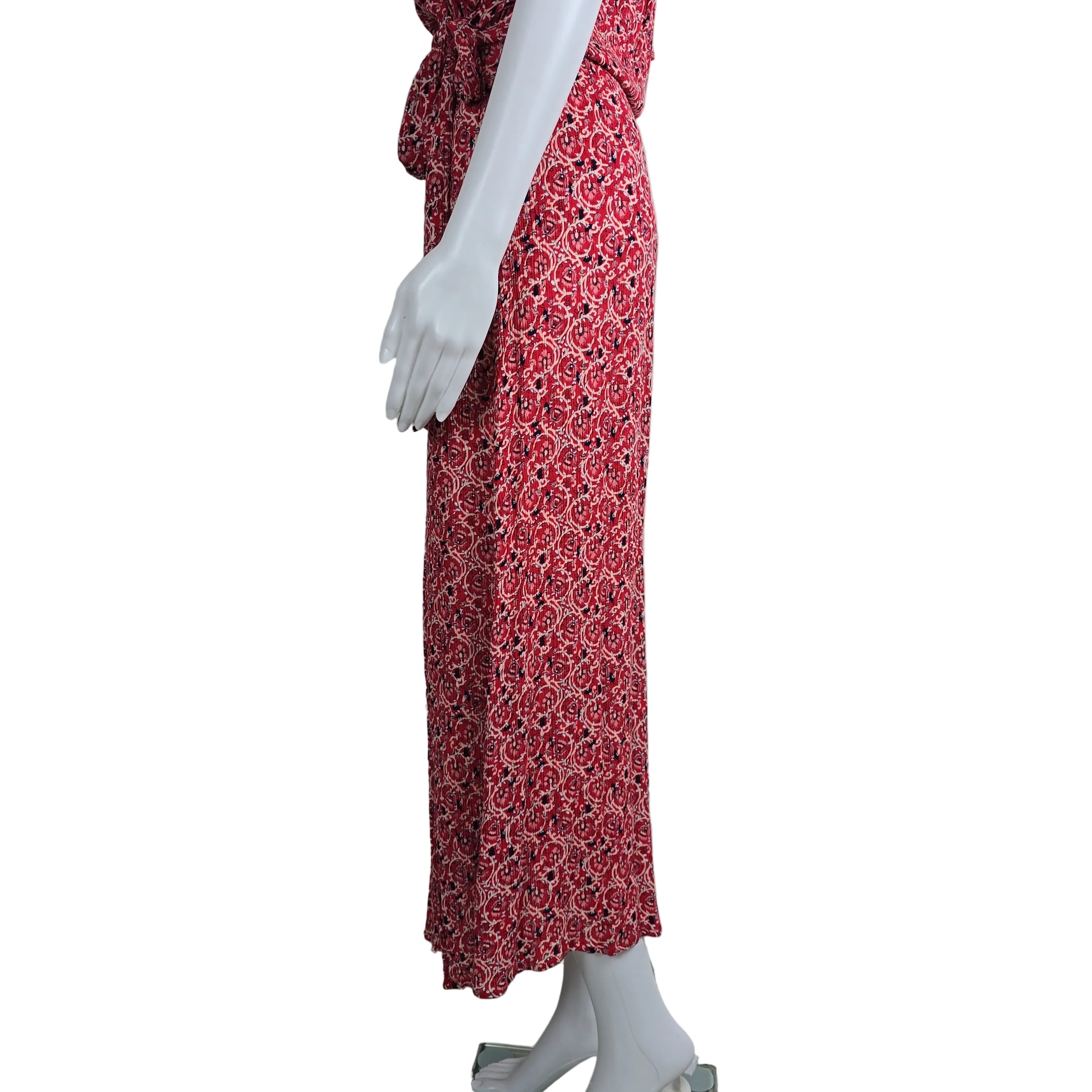 Red patterned fabric draped over a mannequin against a white wall.