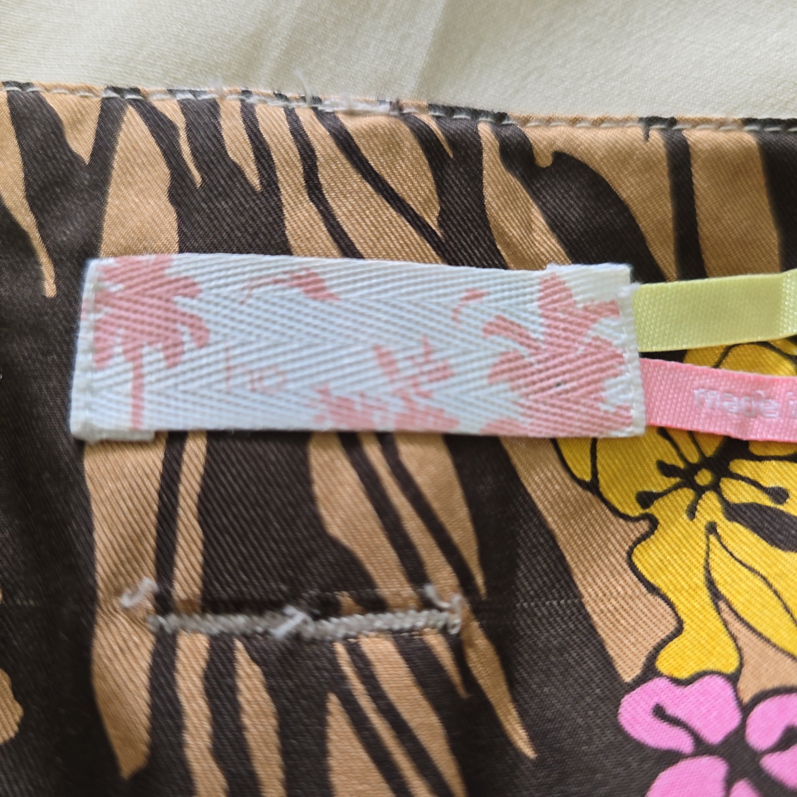 Close-up of a fabric with tiger stripe and floral pattern, featuring a visible brand tag.