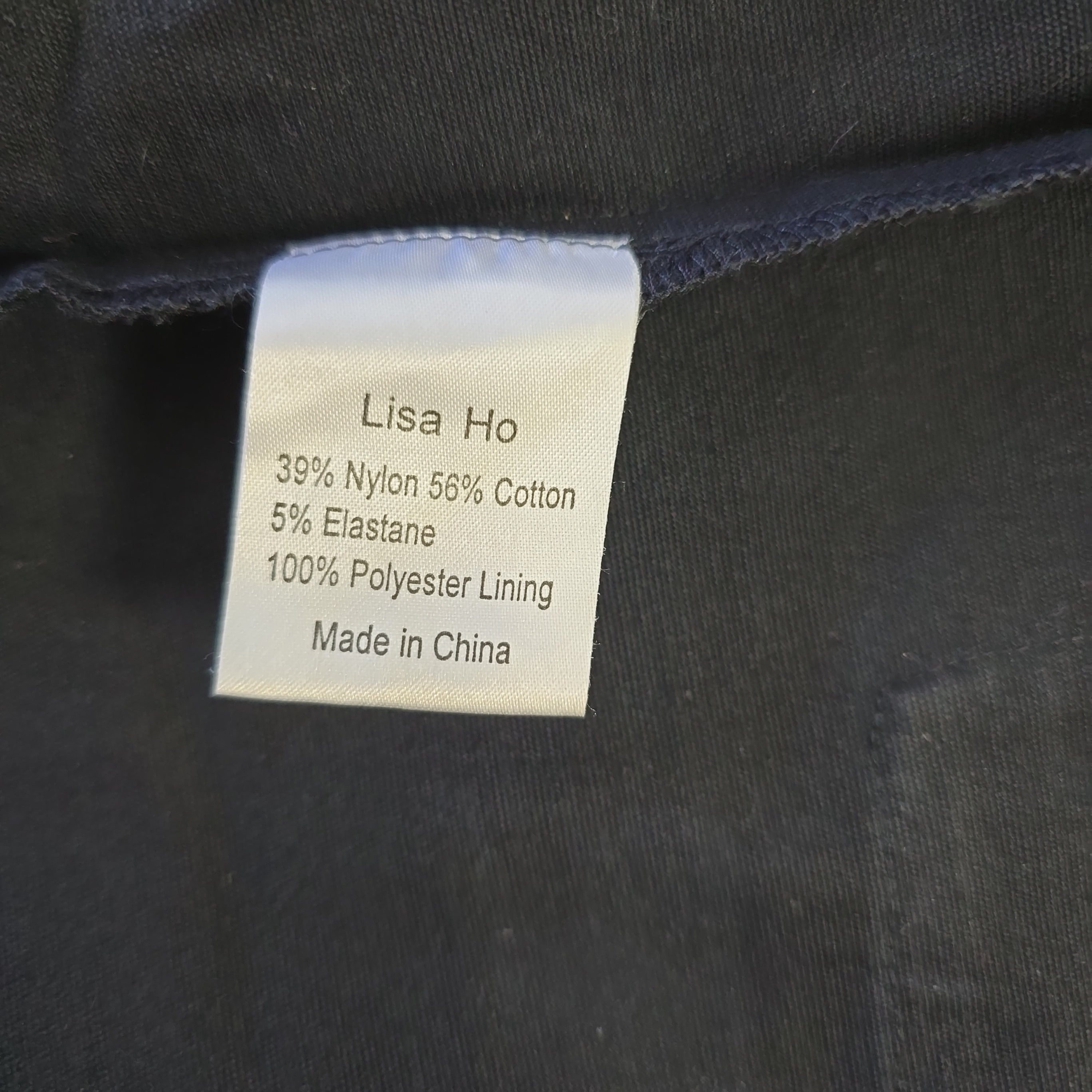 Woven label on a dark fabric with 'Lisa Ho' branding and material details.