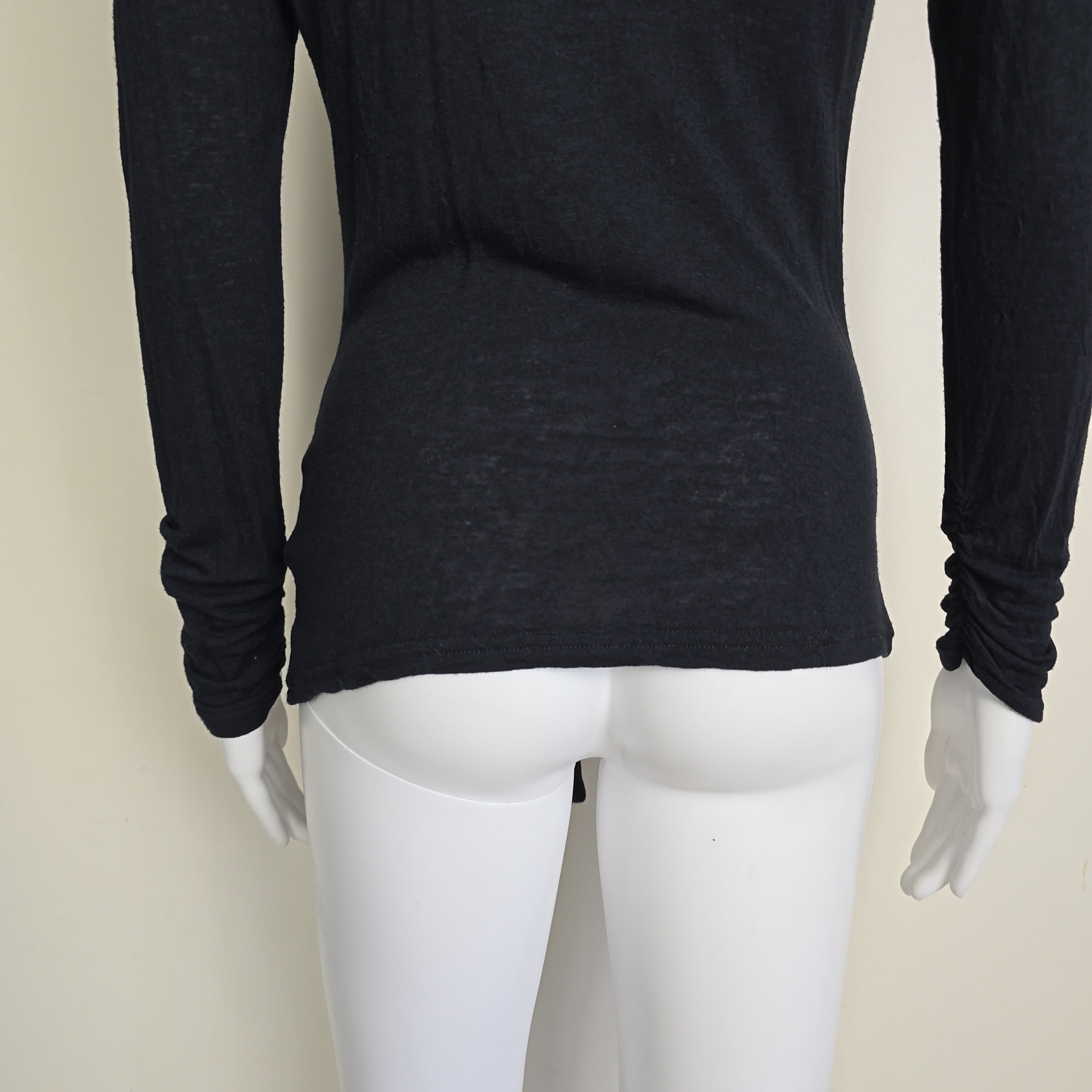 Mannequin wearing a black long-sleeve top on a plain background