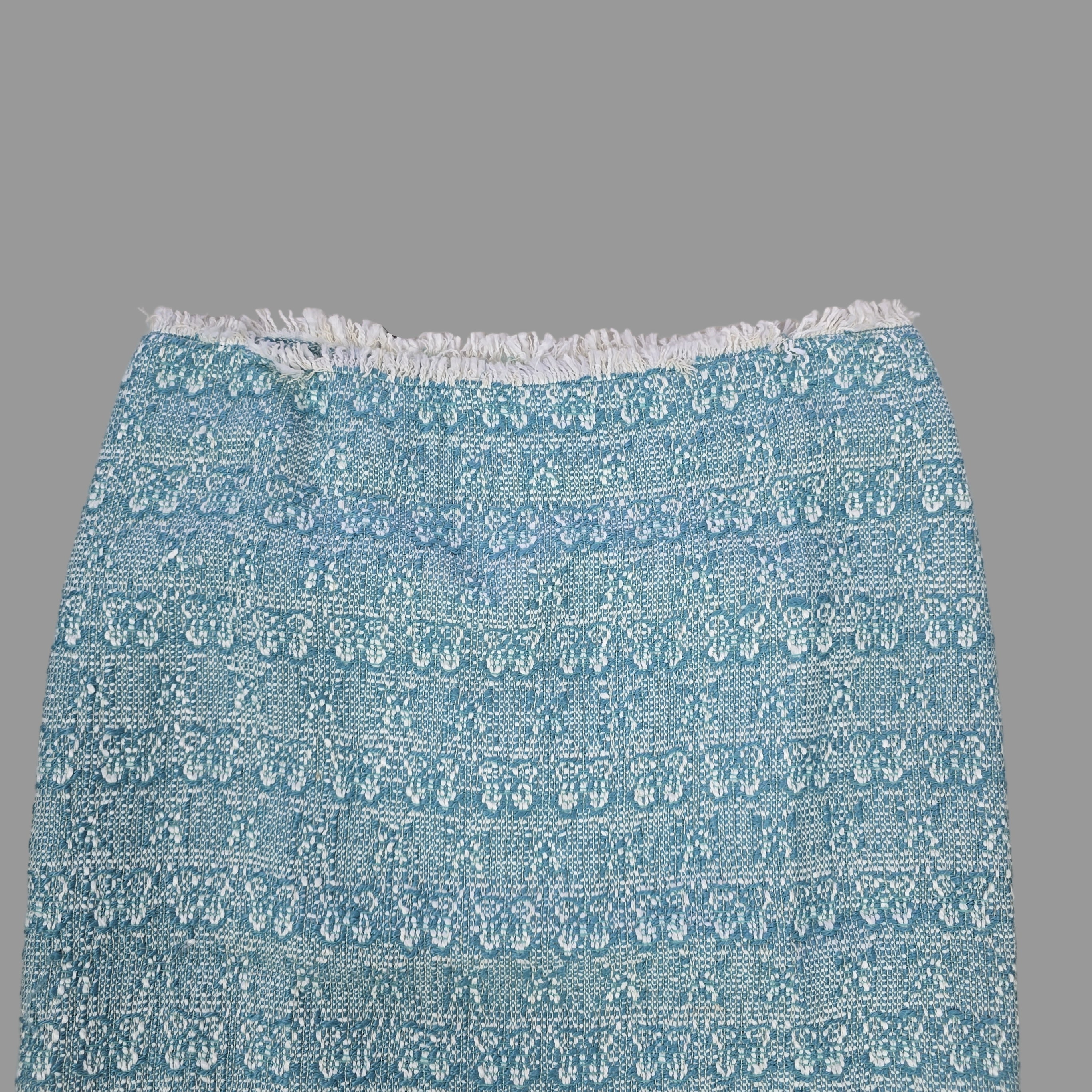 Blue patterned skirt with white fringe on a tiled floor