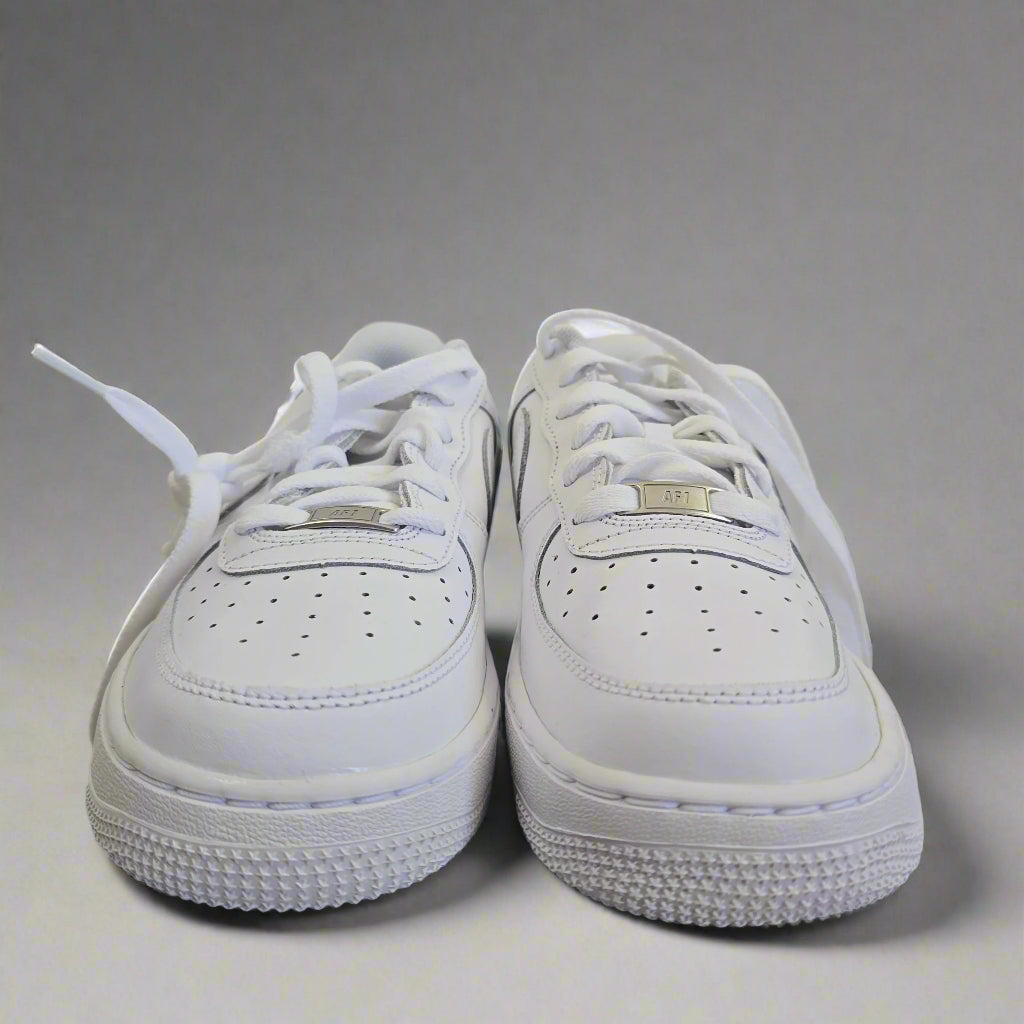 Pair of white sneakers on a light gray surface with a neutral background