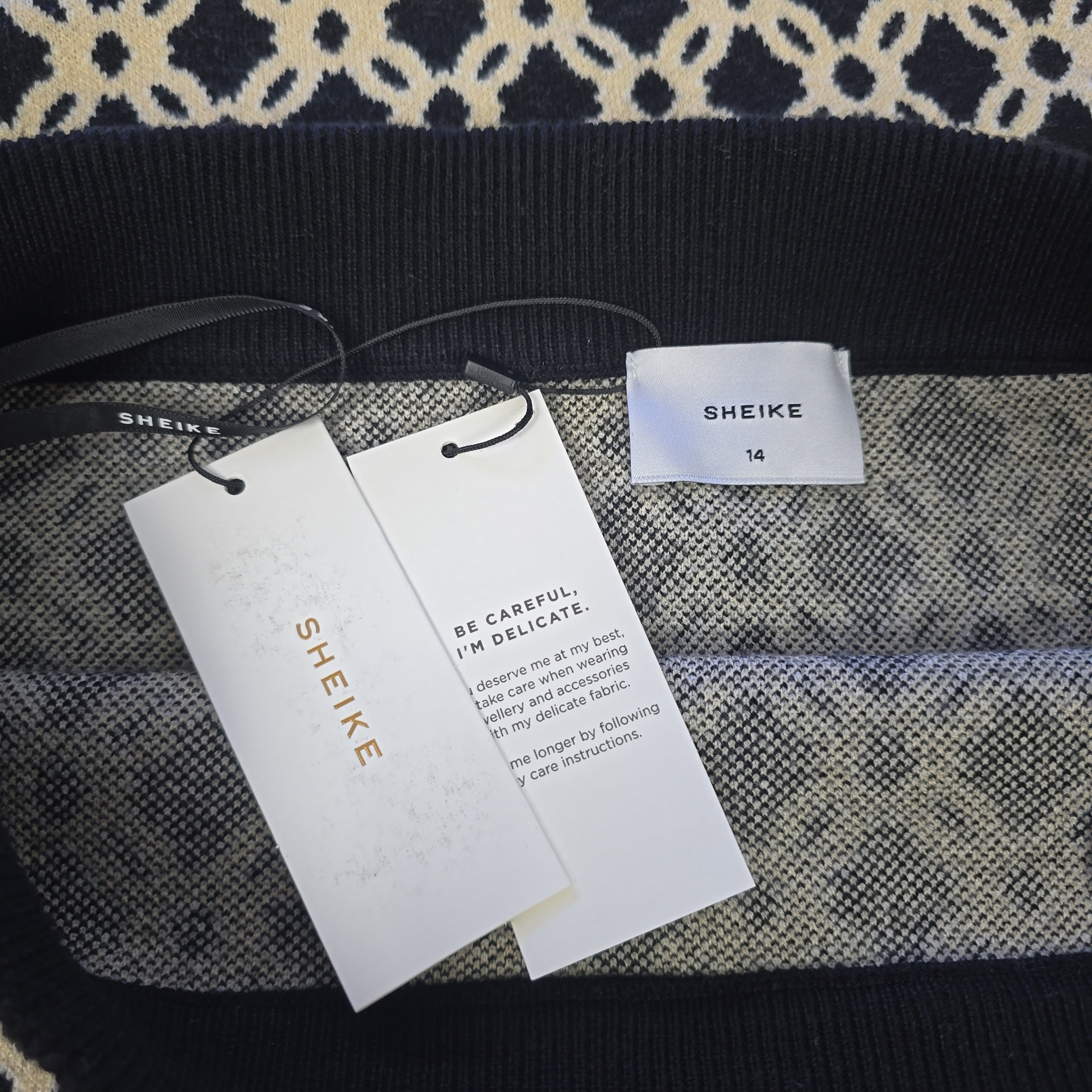 SHEIKE clothing tags on a patterned fabric background