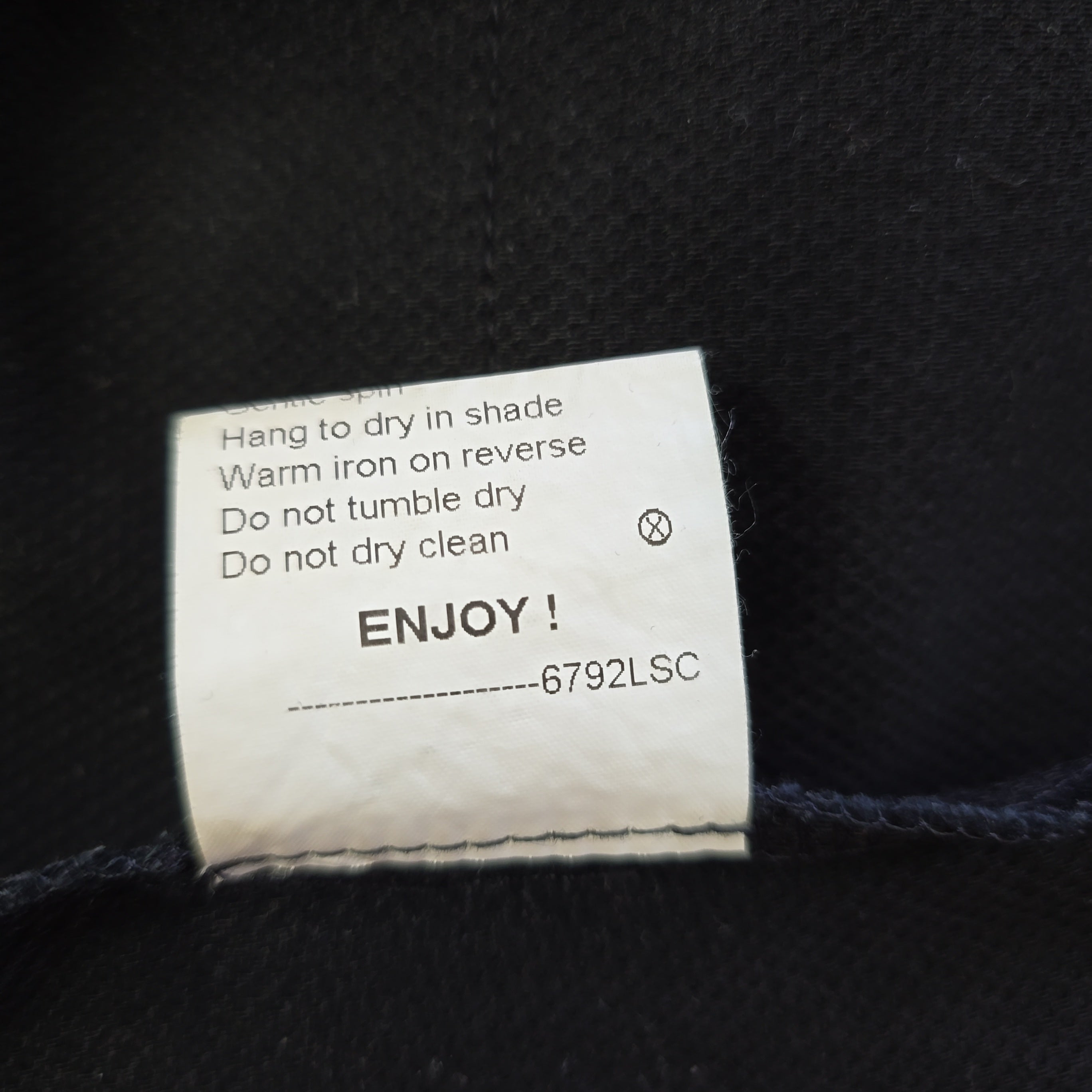 Clothing label with care instructions on a black fabric background