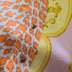 Fabric with orange fish pattern on a yellow and pink background