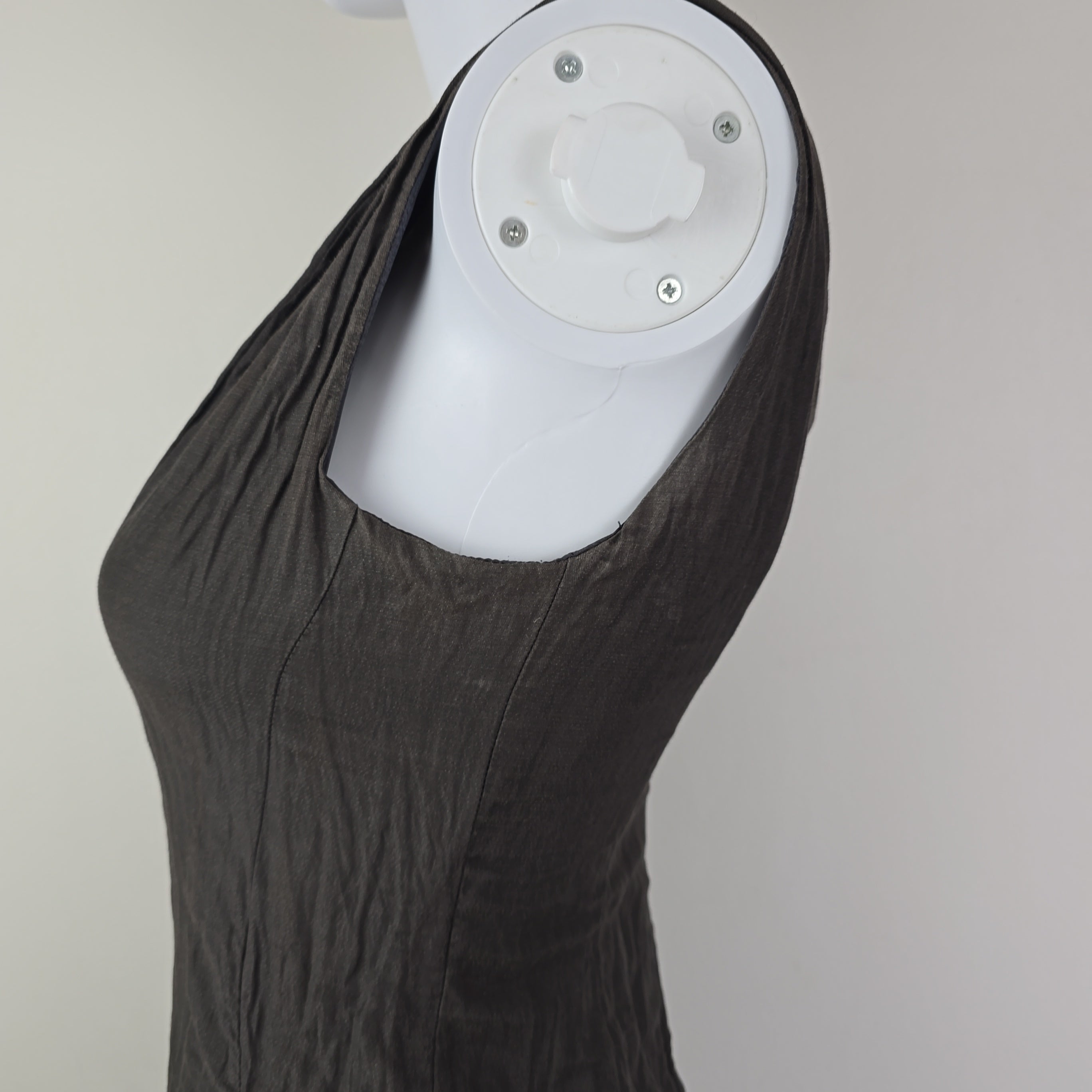 White cylindrical object with a black fabric draped over it on a neutral background