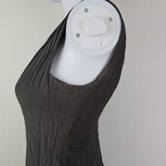 White cylindrical object with a black fabric draped over it on a neutral background