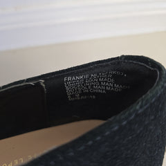 Close-up of a black shoe with brand name on the insole against a neutral background