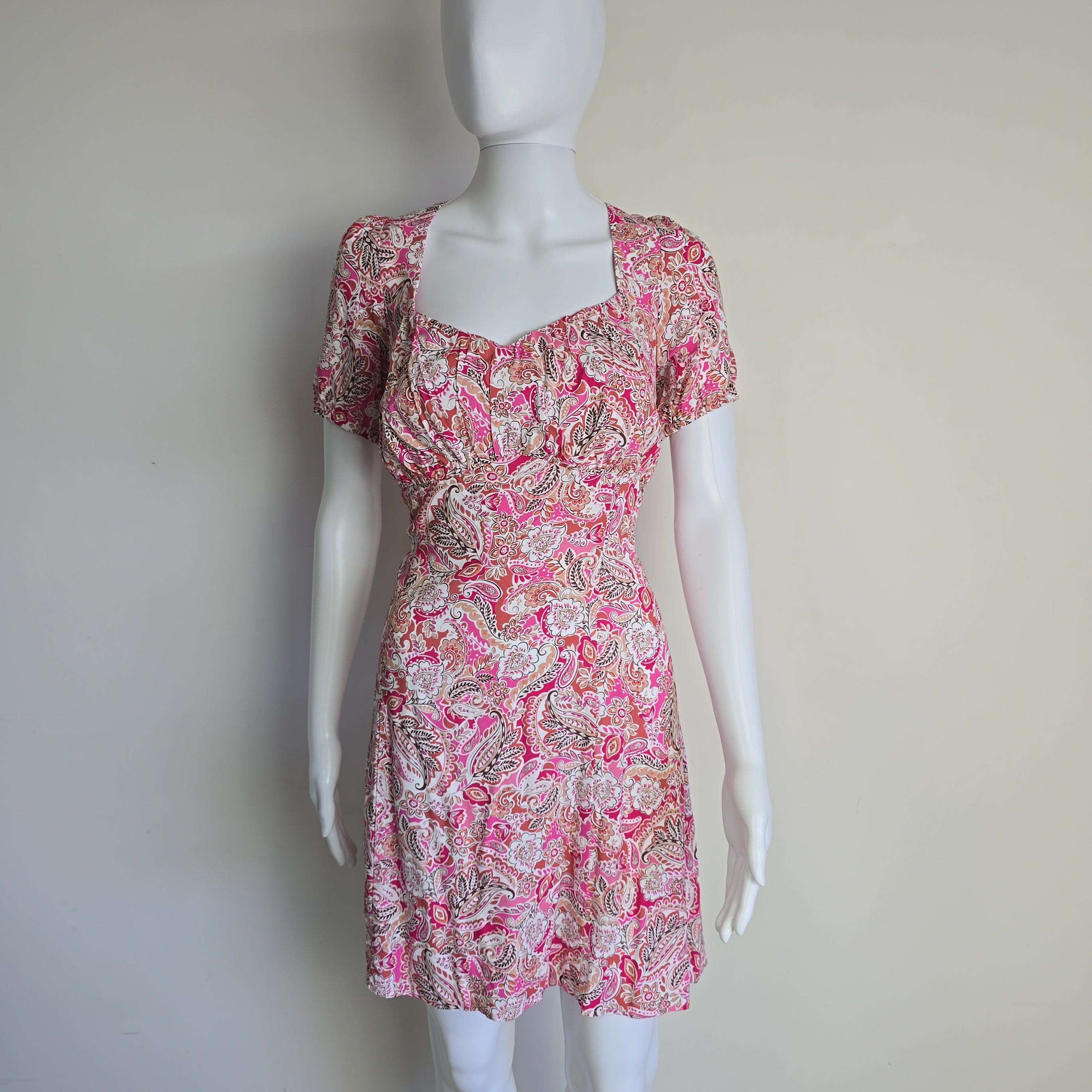 Mannequin wearing a pink floral dress against a plain background