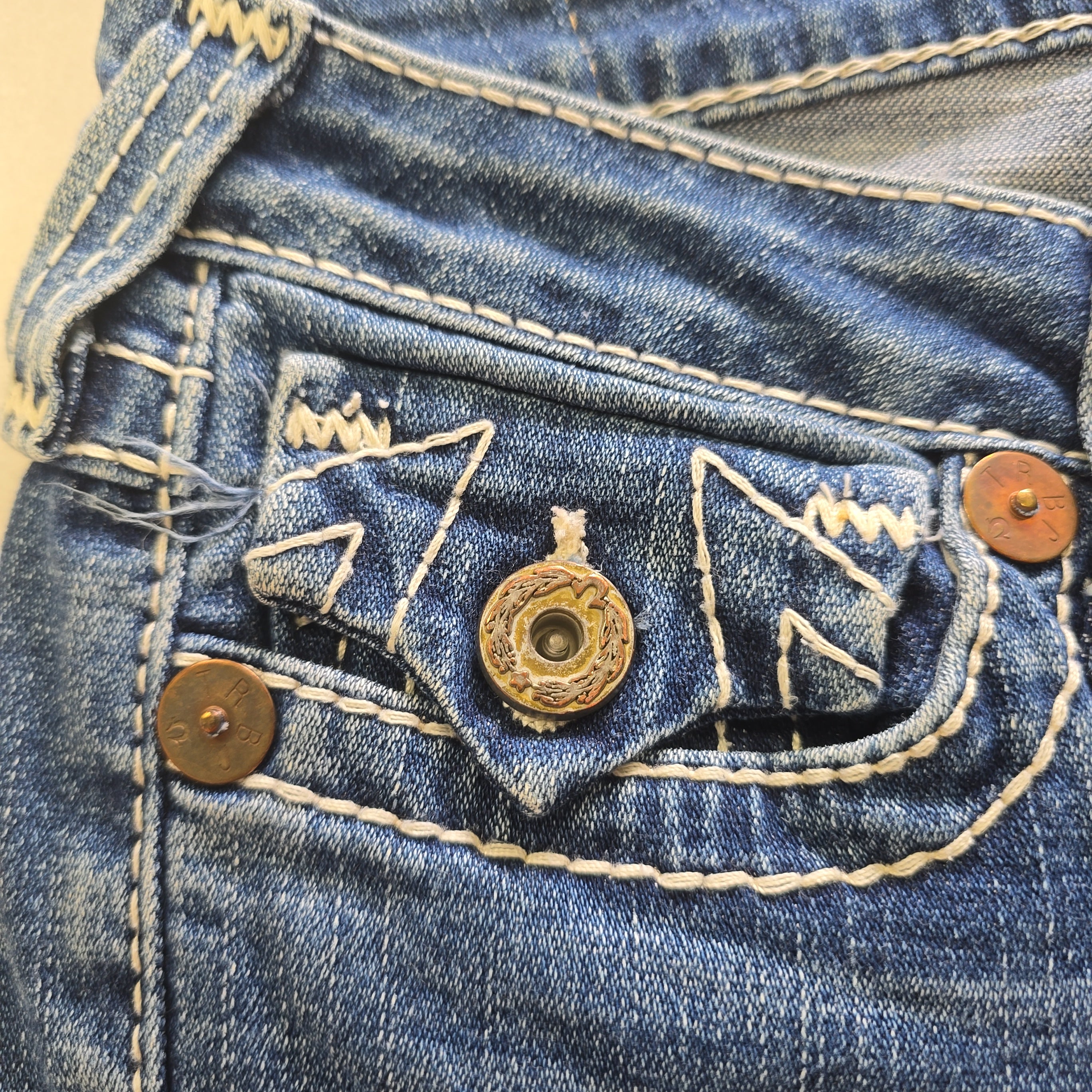 Close-up of a blue denim with buttons and stitching details.