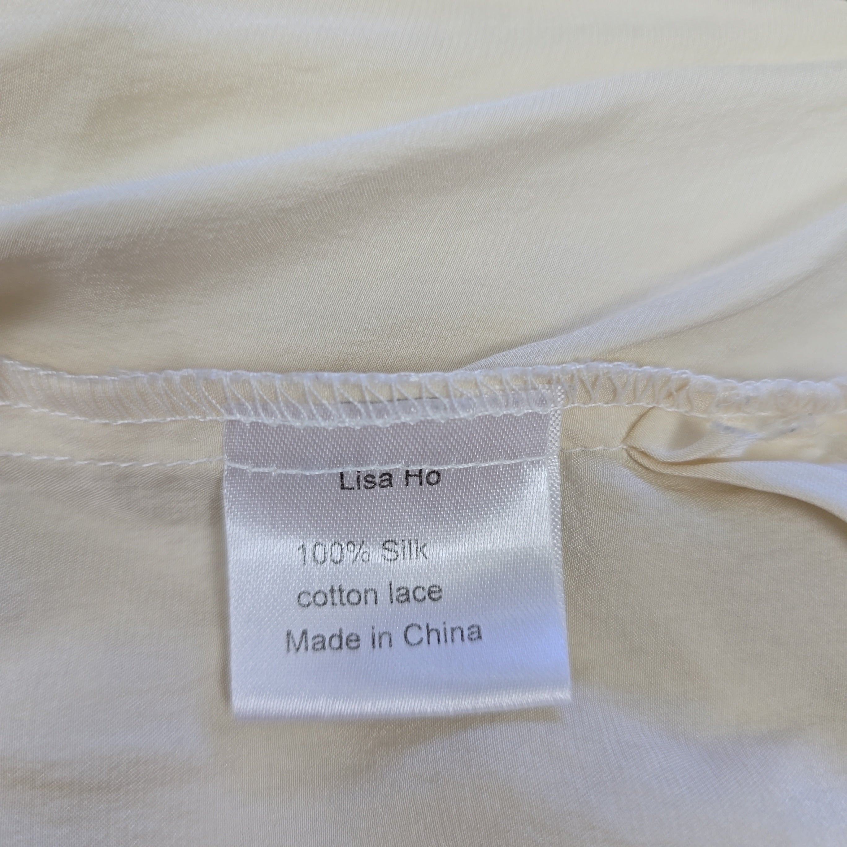 Close-up of a label on a beige garment with text about material and origin.