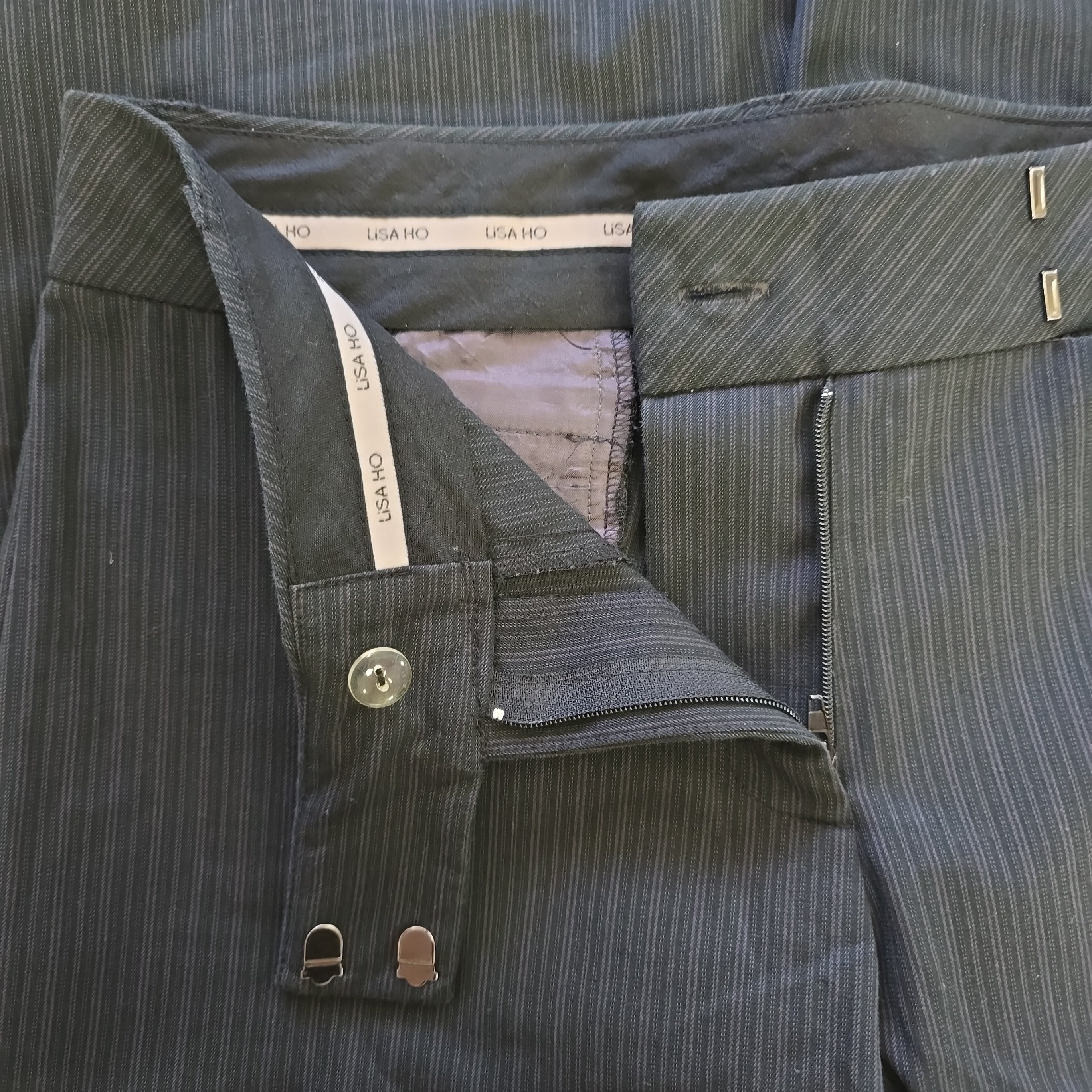 Gray suit pants with buttons and a visible brand label on a neutral background