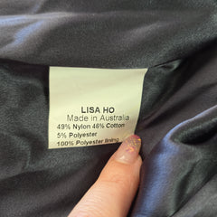 Clothing label on a dark fabric with 'LISA HO' branding.
