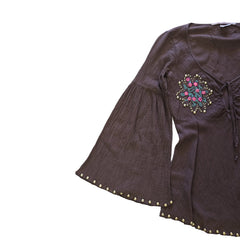 Brown garment with floral embroidery and gold studs on a light background