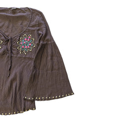 Brown garment with floral embroidery and gold studs on a light background