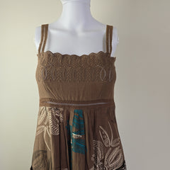 Brown dress with intricate lace and embroidery on a mannequin against a beige background