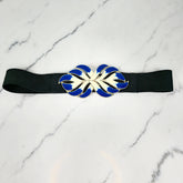 A vintage black, blue, and white elastic belt with an enamel and metal buckle placed on a marble surface.