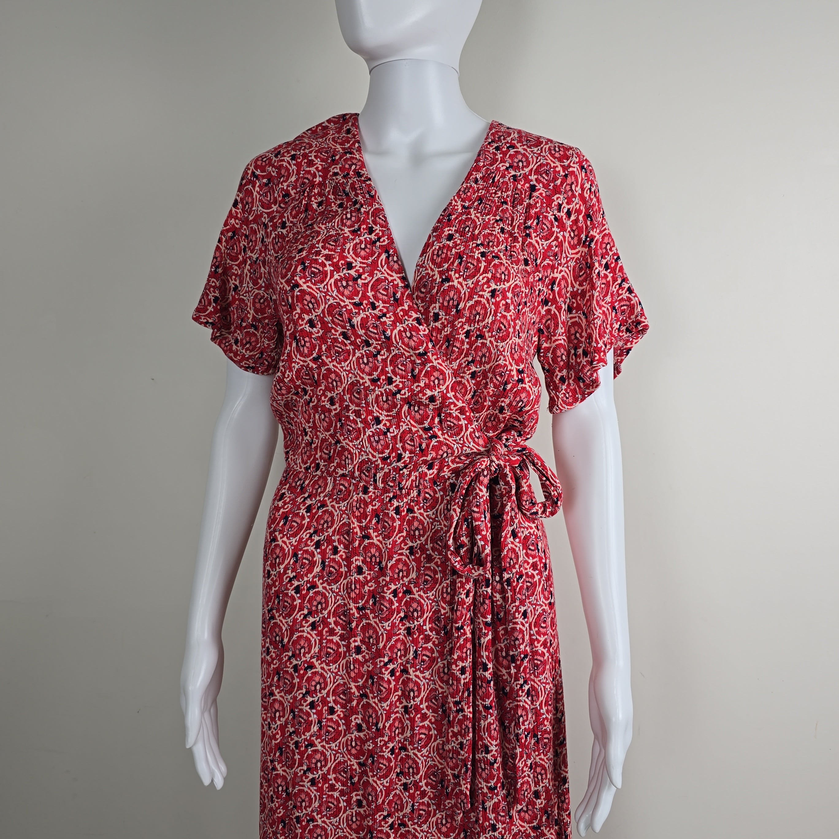 Red patterned dress on a white mannequin against a plain background