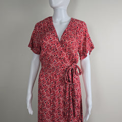 Red patterned dress on a white mannequin against a plain background