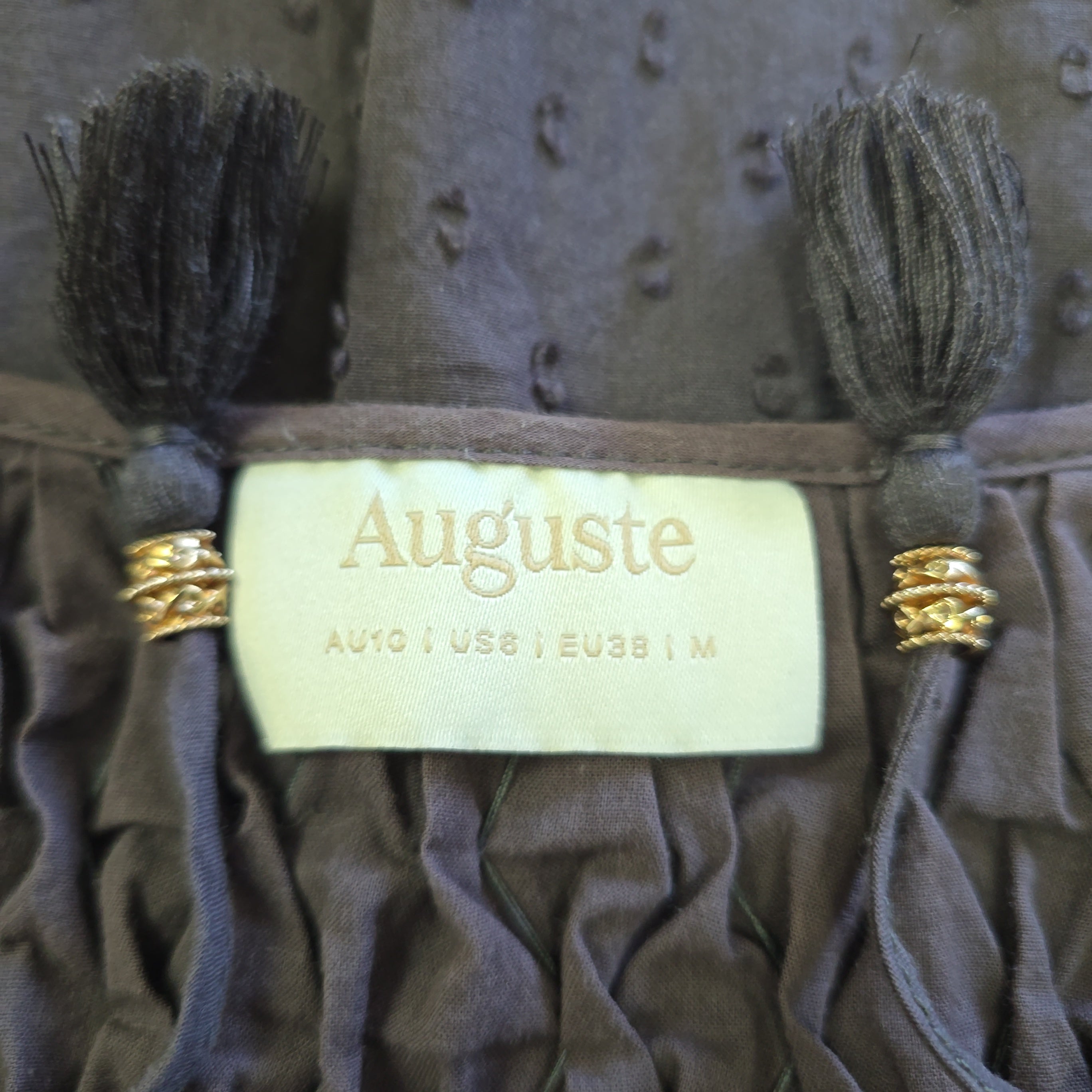 Auguste label with tassels on a textured surface