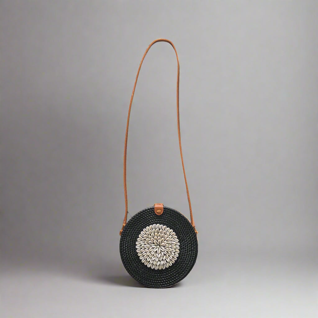 Black woven handbag with a brown strap on a tiled floor